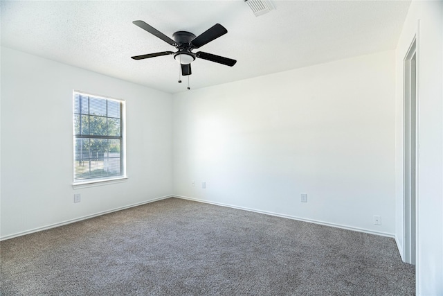 carpeted spare room with ceiling fan, baseboards, visible vents, and a textured ceiling