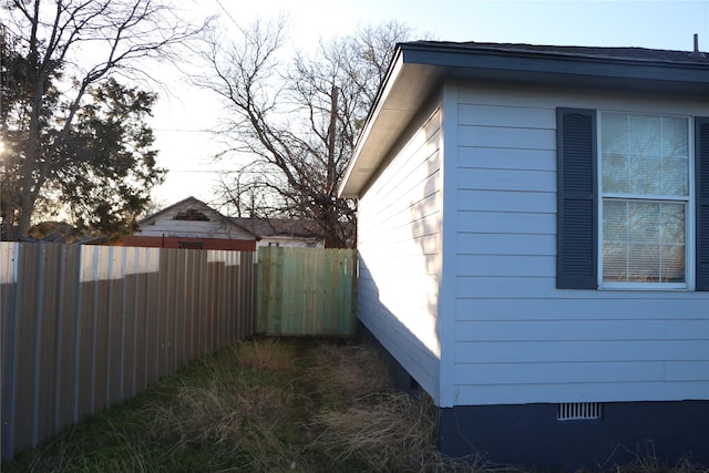 view of side of home featuring fence and crawl space