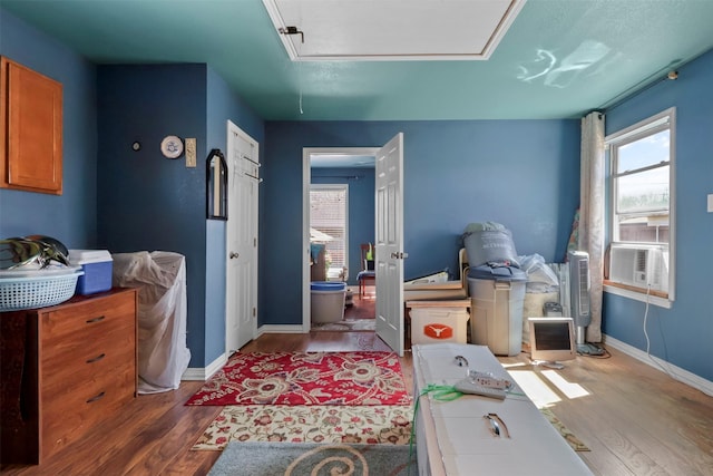 interior space with attic access, cooling unit, wood finished floors, and baseboards