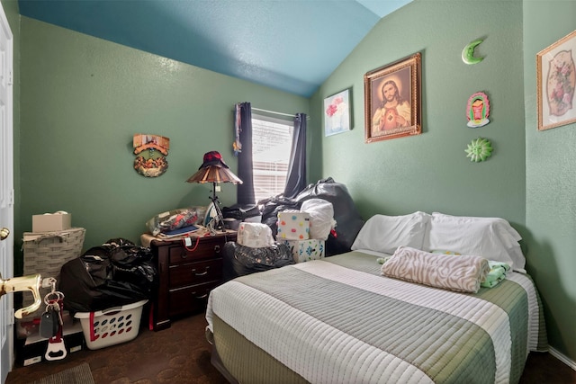 bedroom with dark carpet, lofted ceiling, and a textured wall