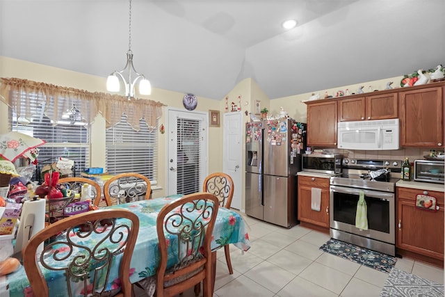 kitchen with light tile patterned floors, brown cabinetry, a toaster, stainless steel appliances, and vaulted ceiling