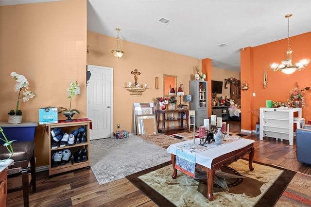 living room with visible vents, baseboards, an inviting chandelier, and wood finished floors