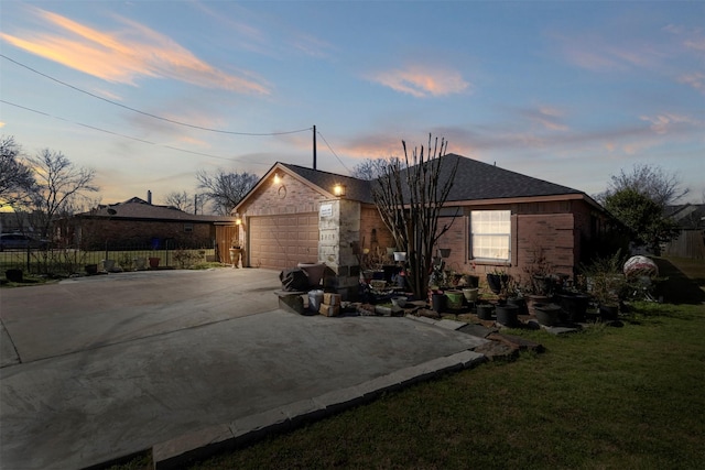 exterior space featuring brick siding, fence, roof with shingles, a lawn, and driveway