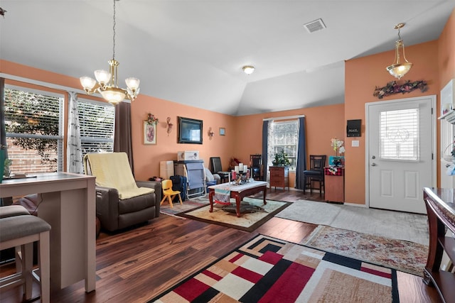 living area with visible vents, plenty of natural light, wood finished floors, and vaulted ceiling