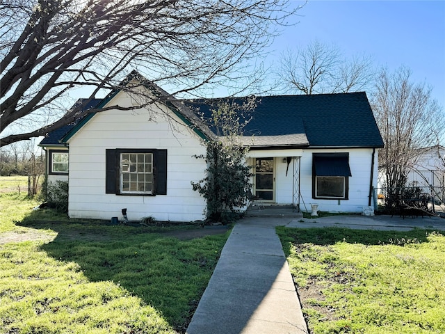 view of front facade featuring a front lawn and a shingled roof