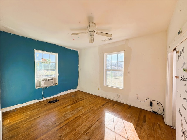 spare room with visible vents, cooling unit, hardwood / wood-style floors, and a ceiling fan