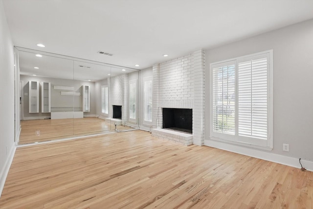 unfurnished living room featuring a brick fireplace, recessed lighting, wood finished floors, and visible vents