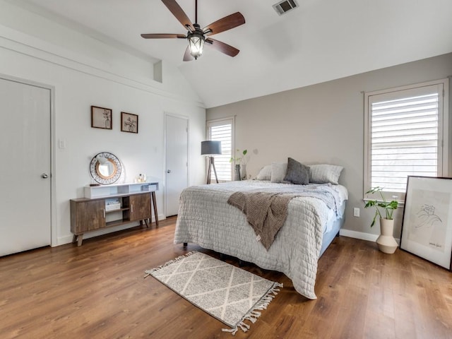 bedroom featuring vaulted ceiling, wood finished floors, visible vents, and baseboards