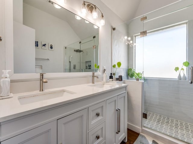 bathroom featuring a stall shower, lofted ceiling, and a sink