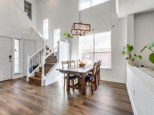 dining area with stairway, baseboards, a notable chandelier, and wood finished floors