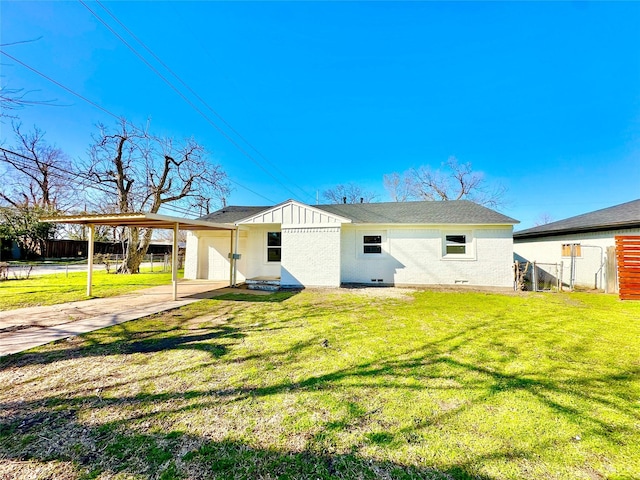 rear view of property featuring fence, a yard, concrete driveway, crawl space, and a carport