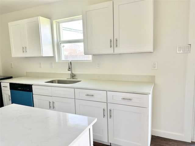 kitchen with dark wood-style floors, dishwashing machine, a sink, baseboards, and white cabinetry