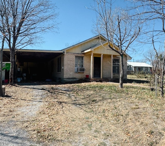 view of front facade featuring cooling unit, brick siding, board and batten siding, and driveway