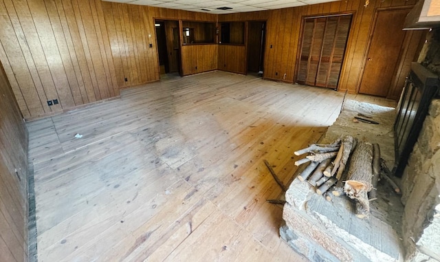 spare room featuring a drop ceiling, light wood-style floors, and wood walls