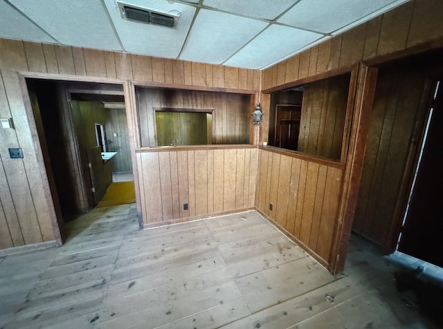 spare room featuring wooden walls, light wood-style floors, and visible vents