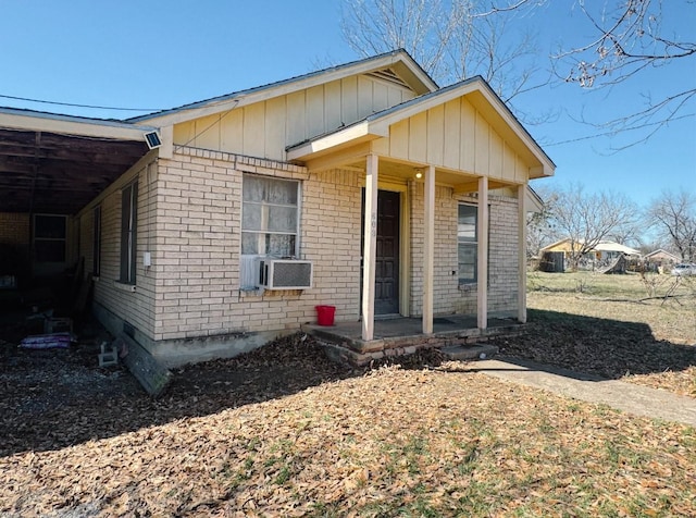 bungalow-style home featuring cooling unit, brick siding, and a porch