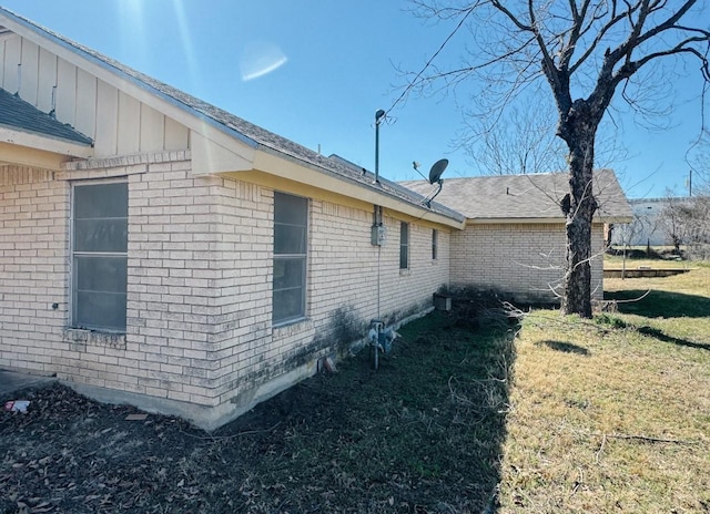 view of property exterior featuring brick siding, a lawn, and board and batten siding