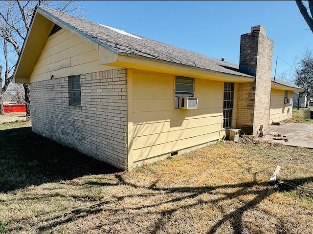 view of side of home with crawl space, cooling unit, brick siding, and a chimney