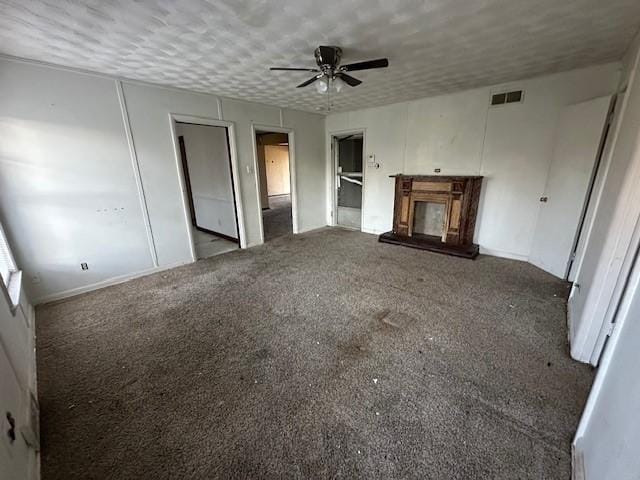 unfurnished living room featuring visible vents, a textured ceiling, a glass covered fireplace, and carpet flooring