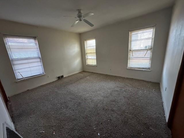 carpeted empty room featuring visible vents and a ceiling fan