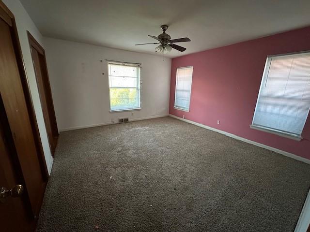 empty room with visible vents, a ceiling fan, baseboards, and carpet floors