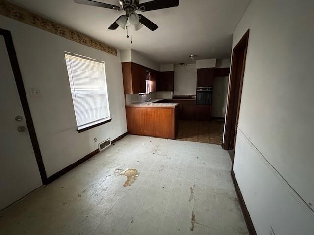 kitchen with visible vents, black oven, backsplash, a peninsula, and ceiling fan