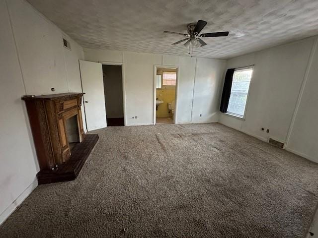 unfurnished living room with a glass covered fireplace, a textured ceiling, carpet floors, and ceiling fan