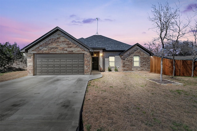 view of front of house with an attached garage, fence, a front yard, roof with shingles, and driveway