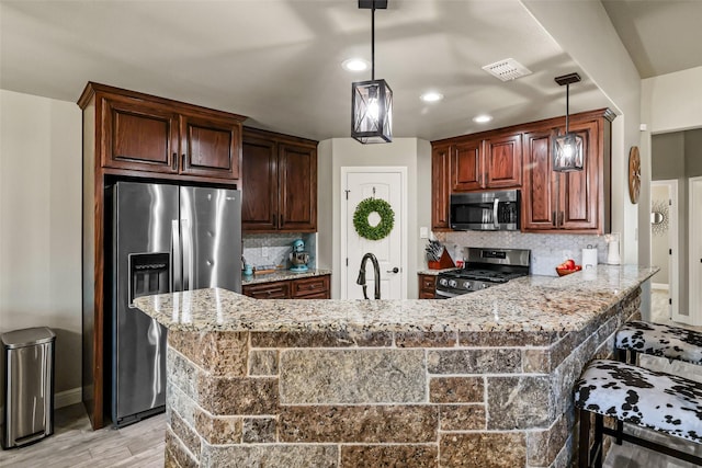 kitchen with tasteful backsplash, visible vents, appliances with stainless steel finishes, and decorative light fixtures