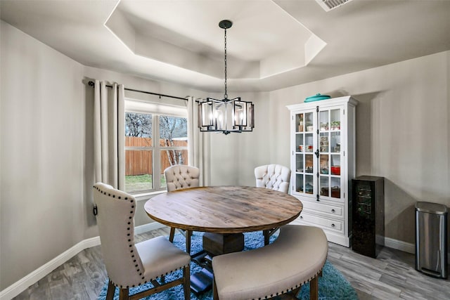 dining area featuring a raised ceiling, wood finished floors, and baseboards