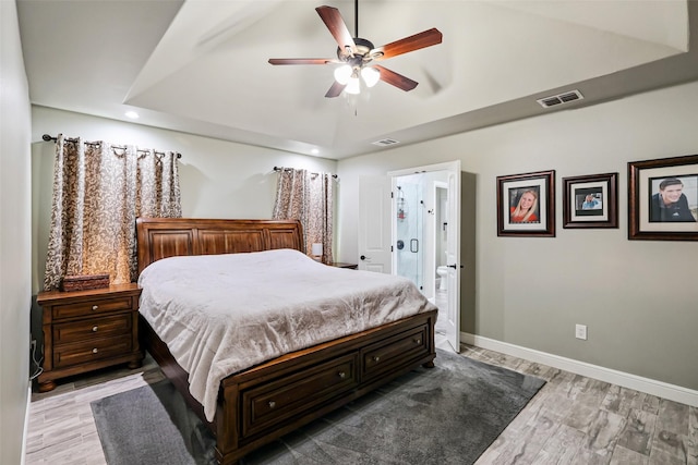 bedroom with visible vents, baseboards, light wood-style floors, and connected bathroom