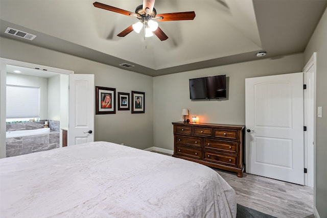 bedroom with visible vents, a raised ceiling, and wood finished floors