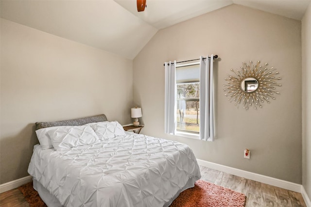 bedroom featuring baseboards, lofted ceiling, and wood finished floors