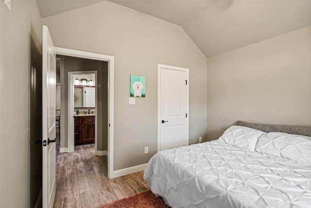 bedroom featuring a sink, light wood-style flooring, baseboards, and vaulted ceiling