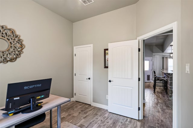 office area with wood finished floors, visible vents, and baseboards