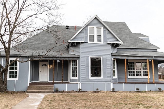 view of front facade with covered porch, a shingled roof, and a front yard