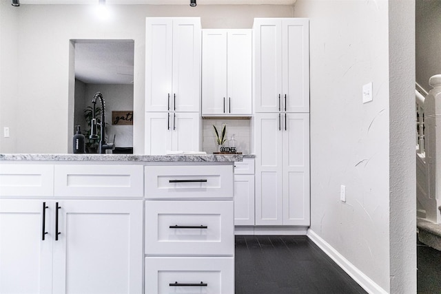 kitchen with light stone counters, baseboards, tasteful backsplash, and white cabinetry