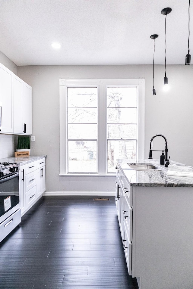 kitchen with stainless steel gas range oven, dark wood finished floors, light stone countertops, and a sink