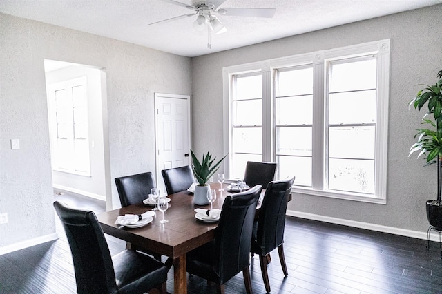 dining space featuring dark wood-type flooring, baseboards, and a textured wall