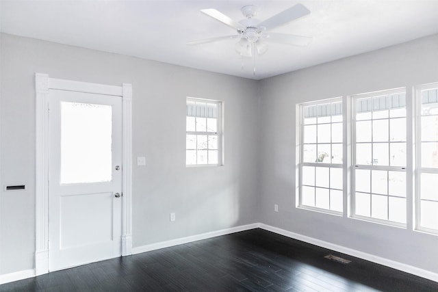 unfurnished room featuring baseboards, dark wood finished floors, and a ceiling fan