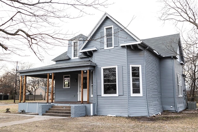 view of front facade with central air condition unit, covered porch, and a shingled roof