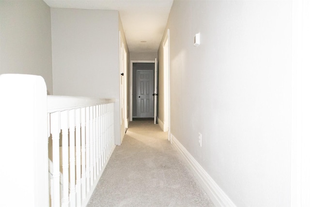 hallway featuring baseboards and light carpet