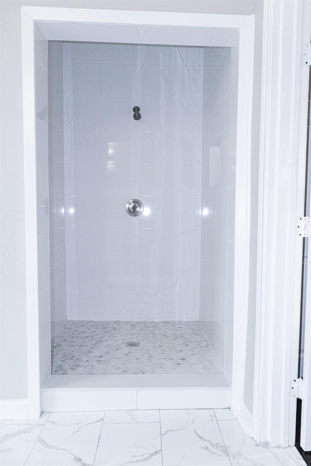 bathroom featuring tiled shower and marble finish floor