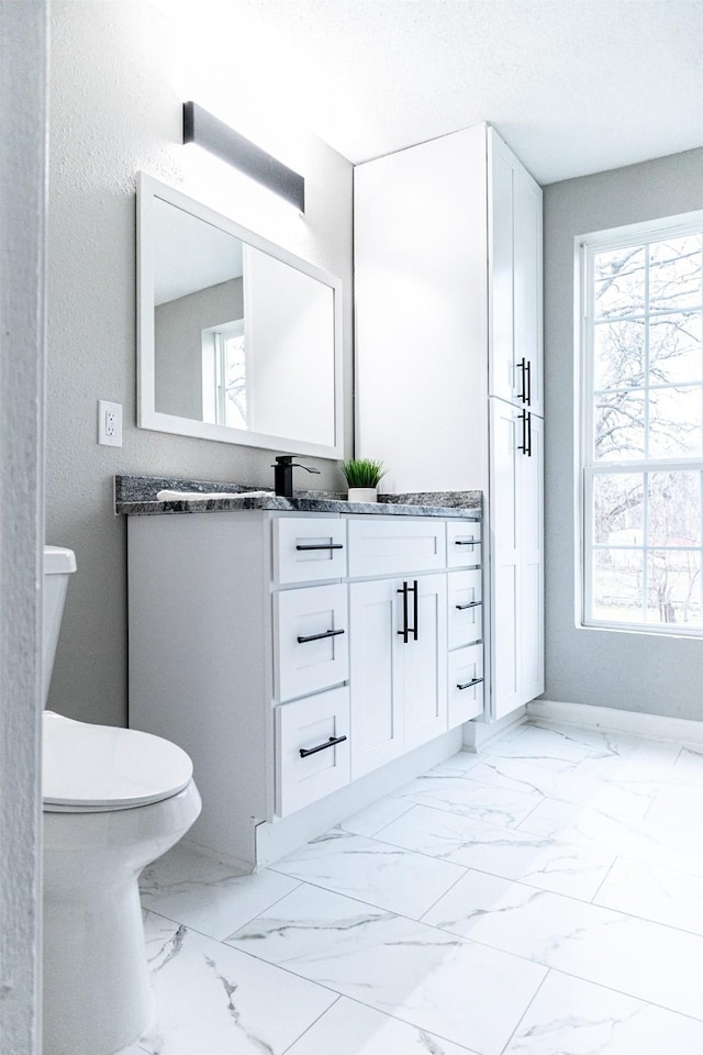 bathroom featuring toilet, marble finish floor, a textured ceiling, baseboards, and vanity