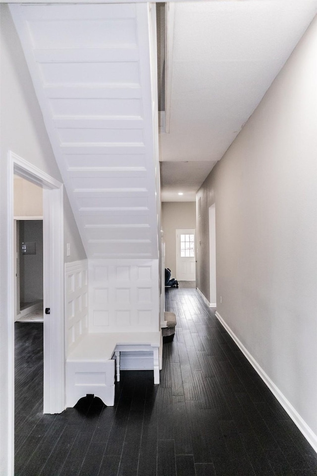 hall with baseboards and dark wood-type flooring