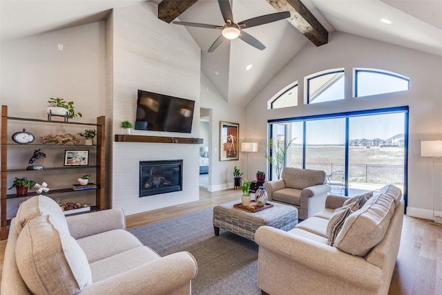 living room with wood finished floors, baseboards, high vaulted ceiling, beamed ceiling, and a large fireplace