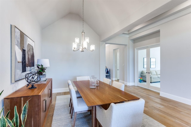 dining area with french doors, light wood-type flooring, baseboards, lofted ceiling, and an inviting chandelier