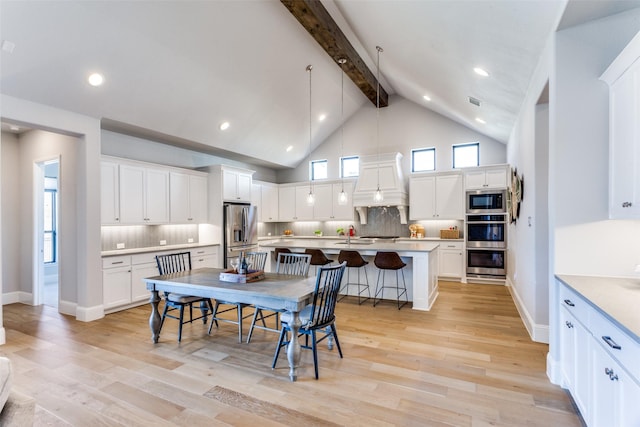 dining area with beam ceiling, baseboards, light wood finished floors, and high vaulted ceiling