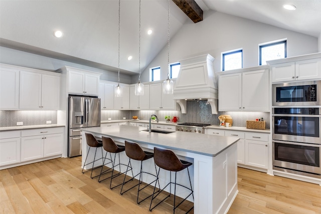 kitchen with premium range hood, a sink, a kitchen breakfast bar, stainless steel appliances, and light wood-style floors