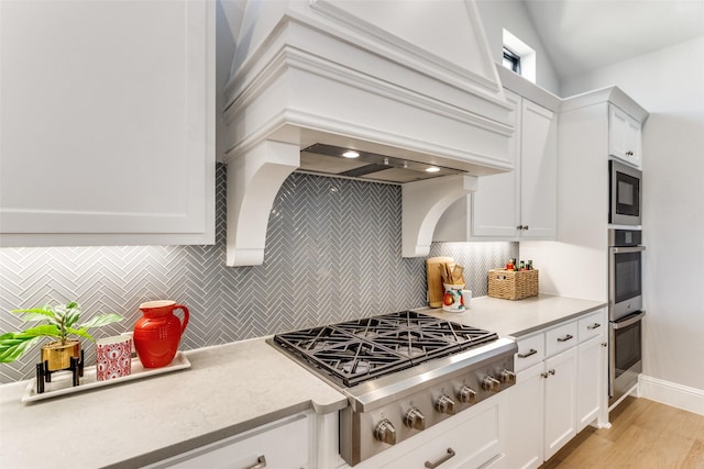 kitchen featuring premium range hood, stainless steel appliances, white cabinets, and light countertops